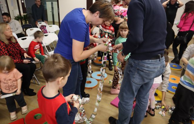 dzieci z rodzicami robią łańcuch na choinkę