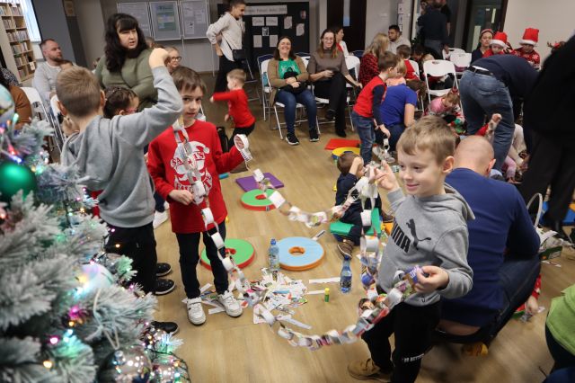 dzieci z rodzicami robią łańcuch na choinkę