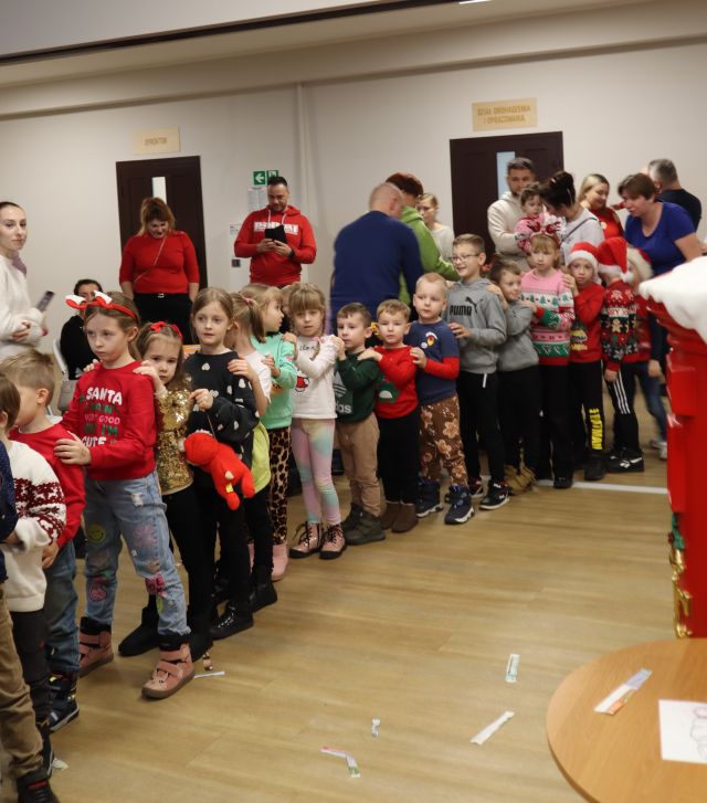 dzieci z rodzicami tworzą długą kolejkę trzymając się za ramiona jeden za drugim