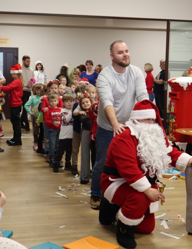 dzieci z rodzicami tworzą długą kolejkę trzymając się za ramiona jeden za drugim