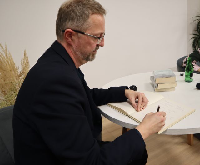 mężczyzna wpisuje się do kroniki biblioteki