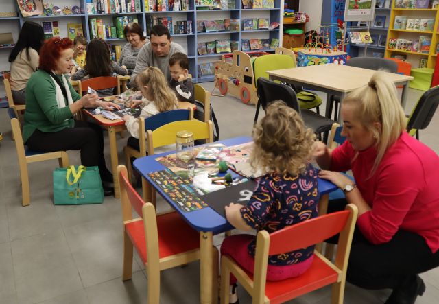 dzieci z rodzicami siedzą przy stolikach, na stolikach materiały plastyczne