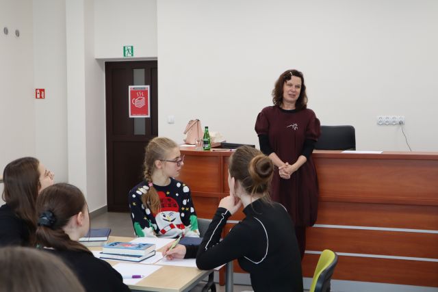 przed siedzącą przy stolikach młodzieżą stoi kobieta