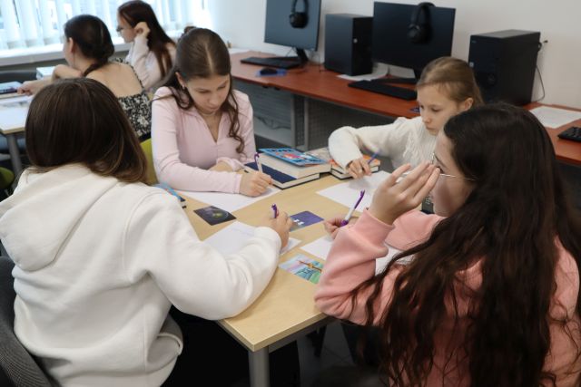 młodzież pisze na kartkach siedząc przy stoliku