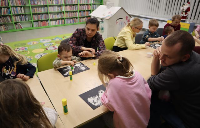 dzieci z rodzicami malują na kartkach