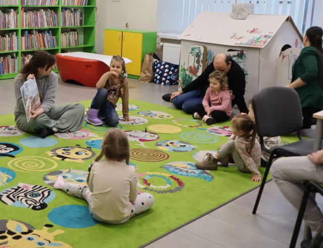 dzieci z rodzicami siedzą na kolorowym dywanie