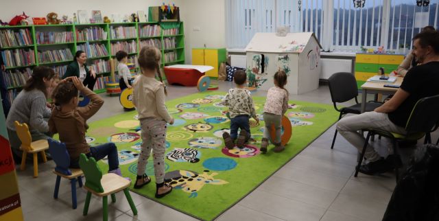 dzieci turlają po kolorowym dywanie okrągłe siedziska