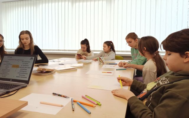 dzieci rysują na kartkach siedząc przy stołach