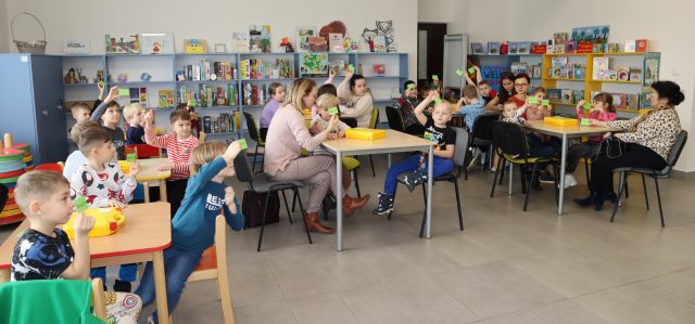 dzieci z rodzicami siedzą przy stołach