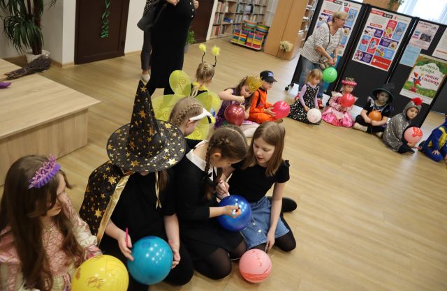 dzieci w różnych przebraniach z rodzicami malują na balonach