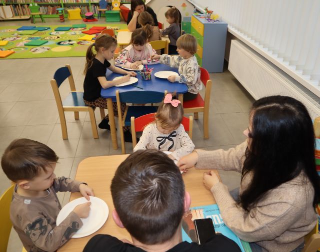 dzieci i rodzice rysują siedząc przy stolikach