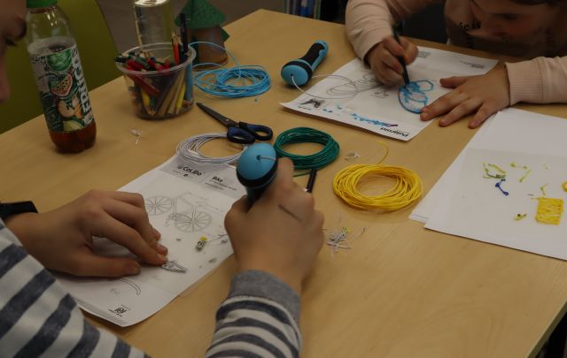 na zdjęciu dłonie dwóch osób trzymające długopisy 3d