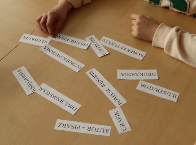 na stole kartki z twórcami książek