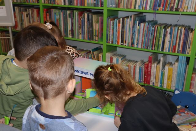dzieci przed kolorowym pudełkiem, w tle regały z książkami