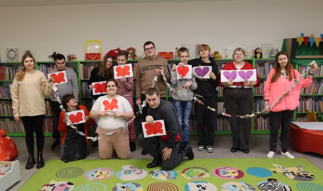 młodzież pozuje do zdjęcia z wykonanymi przez siebie walentynkami i łańcuchem z kawałków gazety