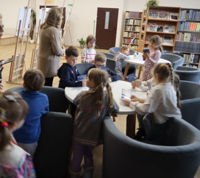 dzieci przy stolikach w czytelni biblioteki