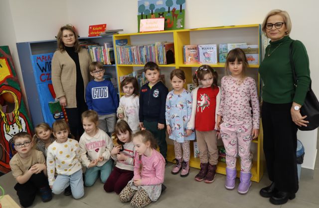 przedszkolaki i dwie kobiety pozują do zdjęcia na tle regałów z książkami
