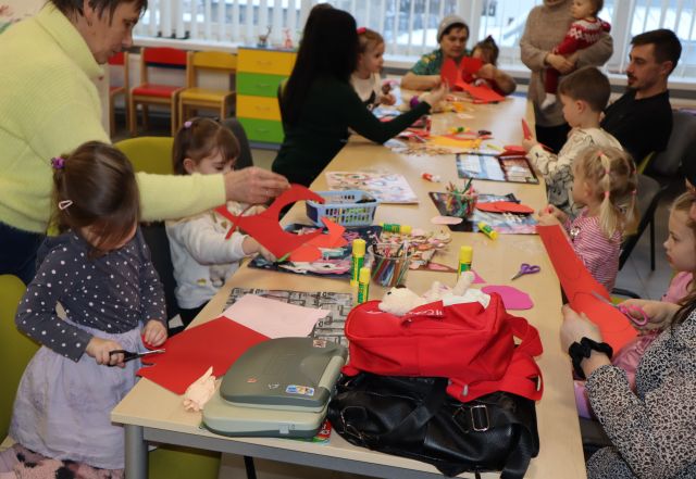 dzieci z rodzicami robią walentynkowe serca z papieru