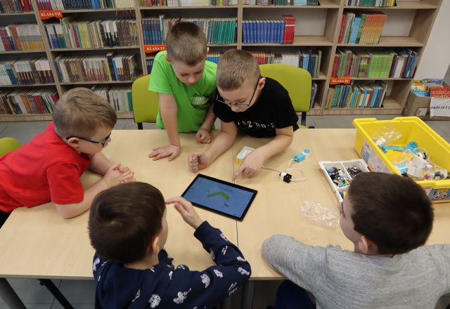 5 chłopców składa klocki Lego używając tableta i kabelków