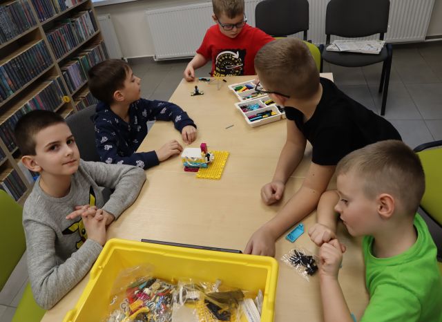 5 chłopców składa klocki Lego używając tableta i kabelków
