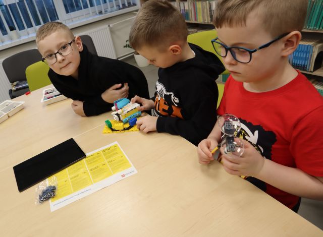 5 chłopców składa klocki Lego używając tableta i kabelków