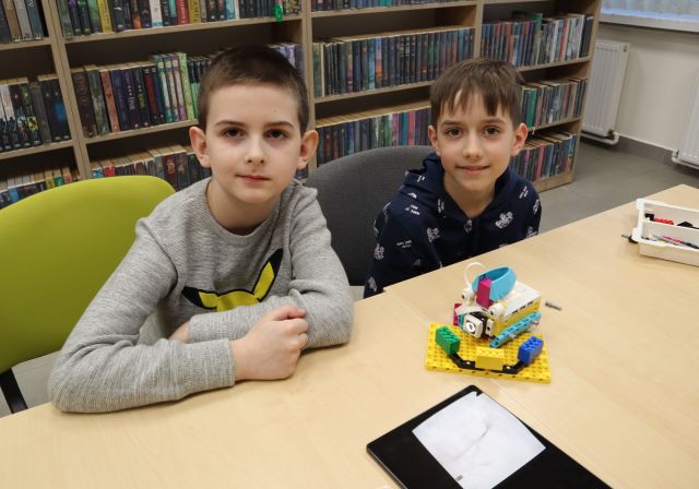 dwóch chłopców prezentuje wykonany przez siebie model z klocków Lego