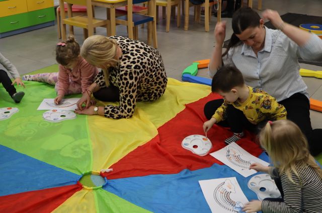 dzieci i rodzice malują dinozaury siedząc na chuście animacyjnej