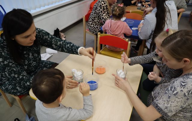 dzieci z rodzicami przekładają pipetką farbkę do słoika