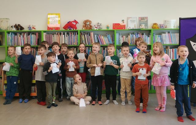 przedszkoalki pozują do zdjęcia ze swoimi pracami, w tle regały z książkami