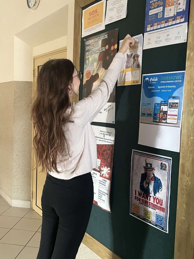 dziewczyna wiesza plakat na tablicy
