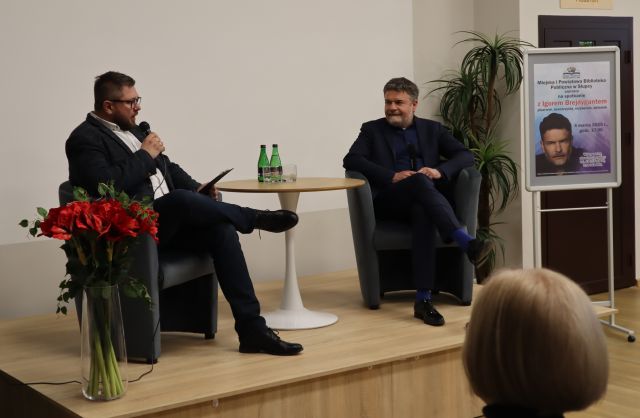 dwóch mężczyzn siedzi na fotelach na podwyższeniu