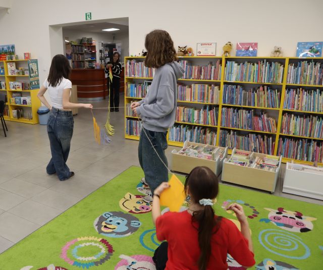 3 młode osoby w przestrzeni bibliotecznej