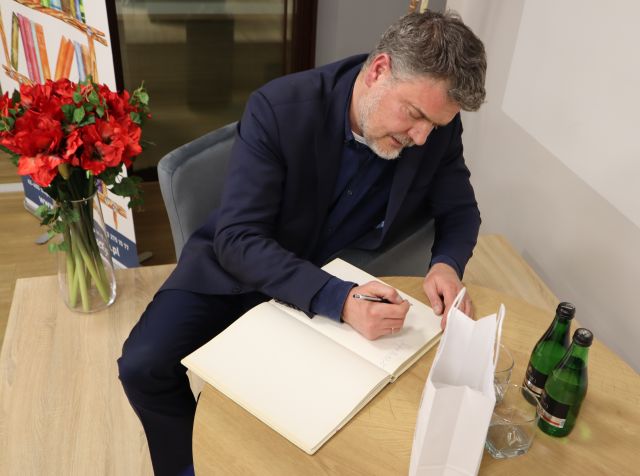 mężczyzna pisze w kronice biblioteki