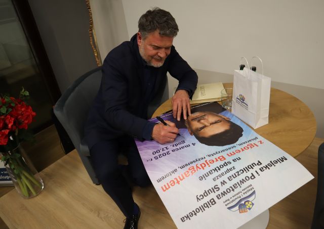mężczyzna podpisuje się na plakacie