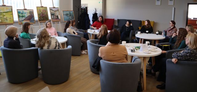 kobiety i mżężczyzna siedzą przy okrągłych stołach