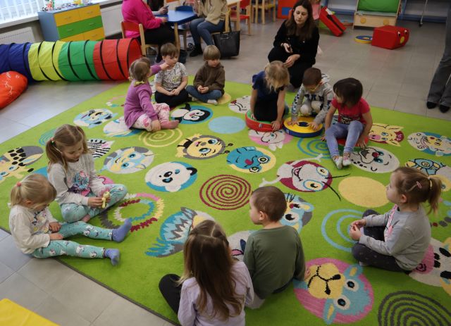 dzieci siedzą na kolorowym dywanie