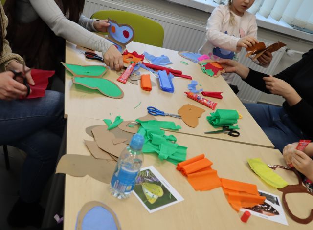 na zdjęciu stoły, a na nich kolorowe papiery, nożyczki, kleje