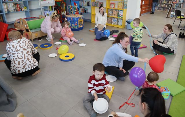 dzieci i rodzice siedzą na podłodze, odbijają balony