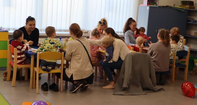 dzieci i rodzice siedzą przy połączonych stołach