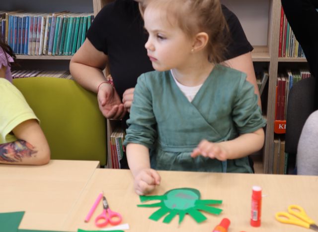 na zdjęciu dziewczynka, przed nią na stole praca plastyczna