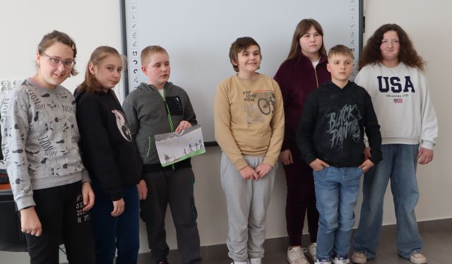 młodzież stoi na tle tablicy interaktywnej i pozuje do zdjęcia