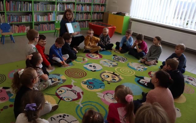 przedszkolaki i bibliotekarka siedzą w kółku na dywanie