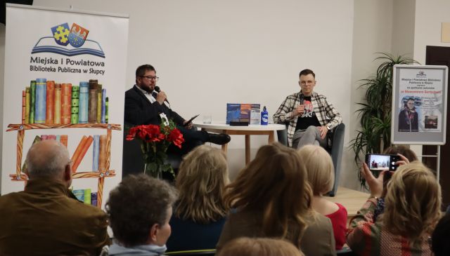 dwóch mężczyzn siedzi na fotelch na scenie