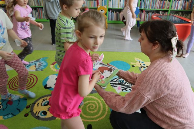 dziewczynka pokazuje bibliotekarce książkę