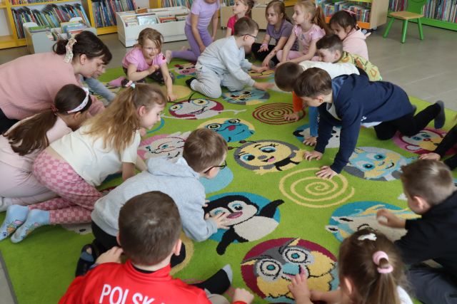 przedszkolaki siedzą na kolorowym dywanie