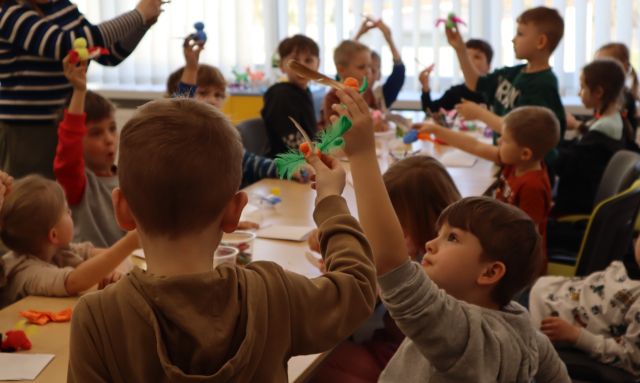 dzieci z podniesionymi do góry rękami z figurkami z plasteliny