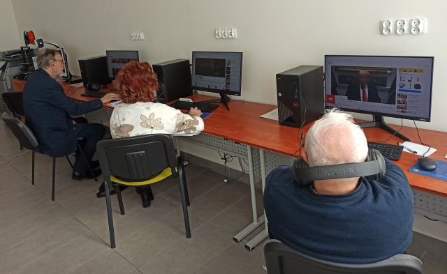 3 seniorów siedzi przed komputerami