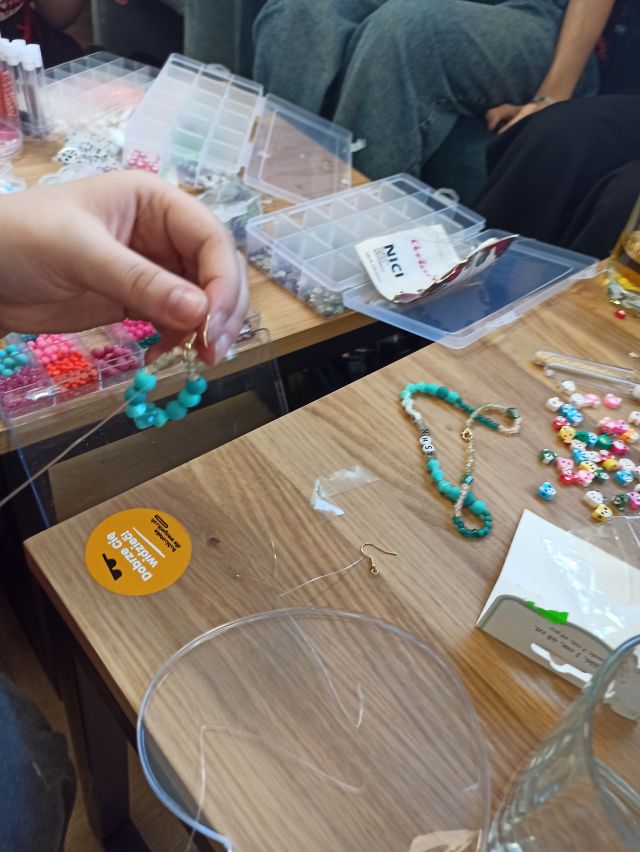 na stole leżą koraliki, miseczki, nożyczki