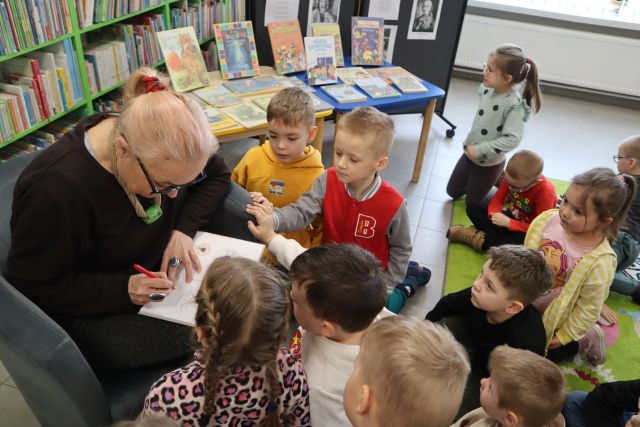 kobieta podpisuje książkę, przed nią gromadzą się przedszkolaki
