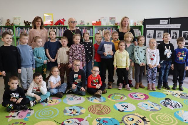 przedszkolaki pozują do zdjęcia z 3 kobietami, w tle regały z książkami